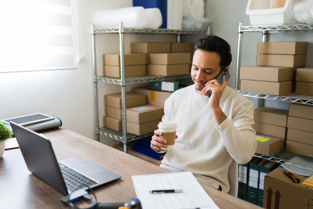 Latin,Entrepreneur,Multitasking,In,His,Small,Business,Warehouse:,Sipping,Coffee,