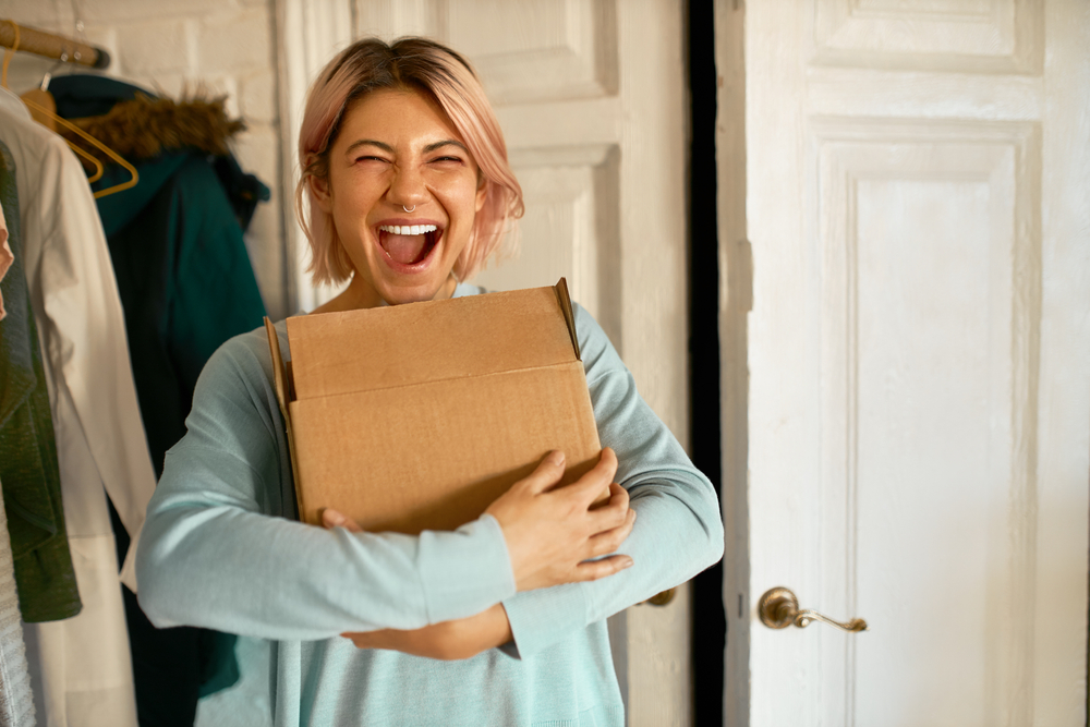 Indoor,Image,Of,Happy,Cheerful,Young,Woman,Holding,Cardboard,Box